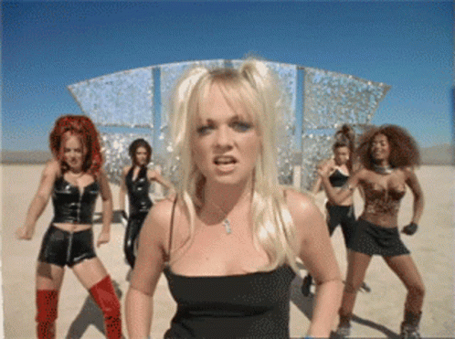 A Blonde Woman In A Black Top Stands In Front Of A Group Of Dancers GIF