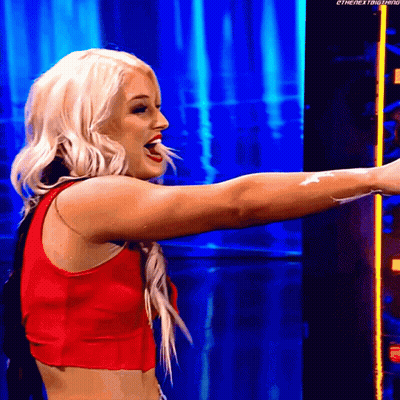 A Blonde Woman In A Red Top Is Standing In Front Of A Blue Background . GIF