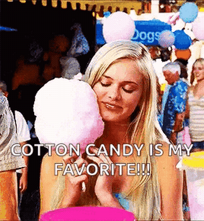 A Blonde Woman Is Eating Cotton Candy At A Carnival . GIF