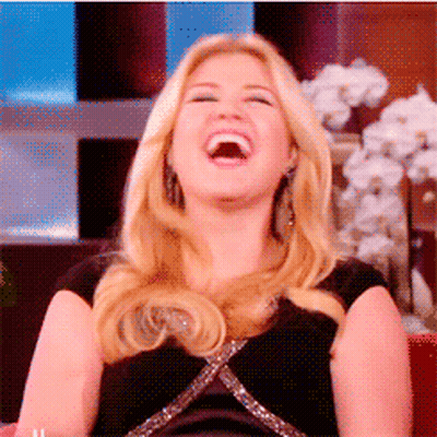 A Blonde Woman Is Laughing With Her Mouth Open GIF