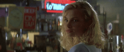 A Blonde Woman Is Smiling In Front Of A Sign That Says No Water To Tap GIF