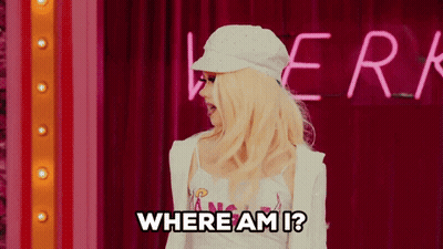A Blonde Woman Is Standing In Front Of A Neon Sign That Says " Where Am I " GIF
