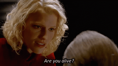 A Blonde Woman Is Talking To A Man In A Dark Room And Asking If He Is Alive . GIF