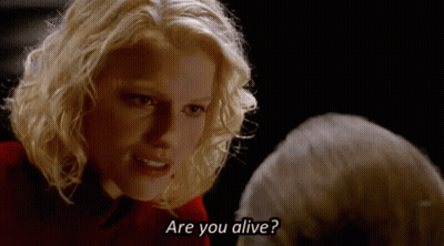 A Blonde Woman Is Talking To A Man In A Dark Room And Asking If He Is Alive . GIF