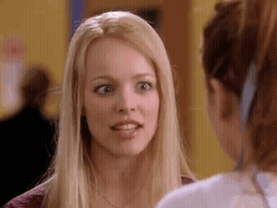 A Blonde Woman Is Talking To Another Woman In A Hallway . GIF