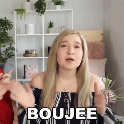 A Blonde Woman Says Boujee In Front Of A Shelf GIF