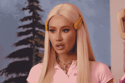 A Blonde Woman Wearing A Pink Shirt With The Letter S On The Front GIF