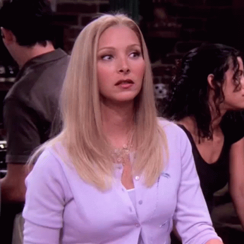 A Blonde Woman Wearing A Purple Cardigan Is Sitting At A Table With Other People . GIF