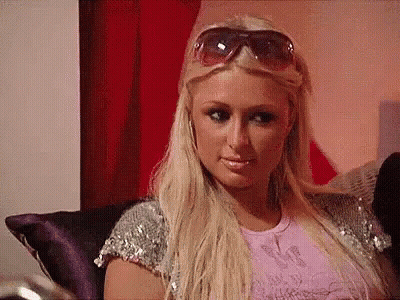 A Blonde Woman Wearing Sunglasses Is Sitting On A Couch . GIF