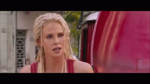 A Blonde Woman With Dreadlocks Is Standing In Front Of A Red Truck GIF