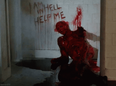 A Bloody Zombie Crawls In Front Of A Wall That Says I Am Hell Help Me GIF