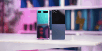 A Blue And A Black Flip Phone Are Sitting On A Table GIF