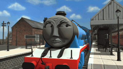 A Blue And Red Train With An Angry Face Is On The Tracks GIF