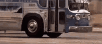 A Blue And White Bus Is Driving Down A Street . GIF