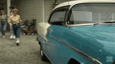 A Blue And White Car Is Parked In A Driveway Next To A Group Of People . GIF