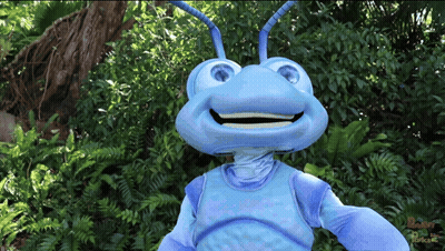 A Blue Ant Mascot Is Smiling In Front Of A Jungle GIF