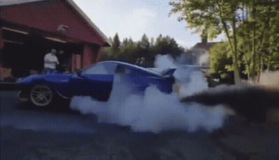 A Blue Car Is Doing A Burnout On A Street GIF