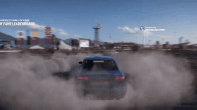 A Blue Car Is Driving Down A Dirt Road In Front Of A Sign That Says ' America 'S Wall Of Fame ' GIF