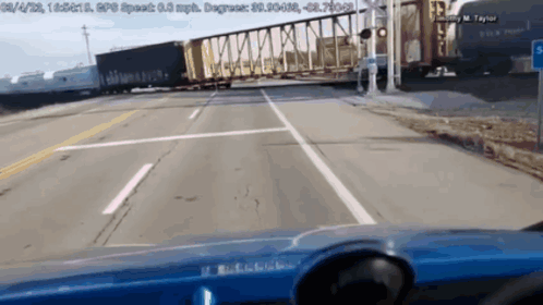 A Blue Car Is Driving Down A Highway Next To A Train GIF