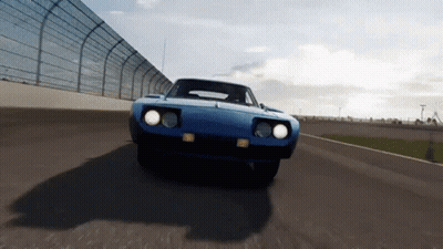 A Blue Car Is Driving Down A Race Track With A Fence In The Background GIF