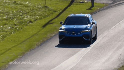 A Blue Car Is Driving Down A Road With Motorweek.org Written On The Bottom Right GIF