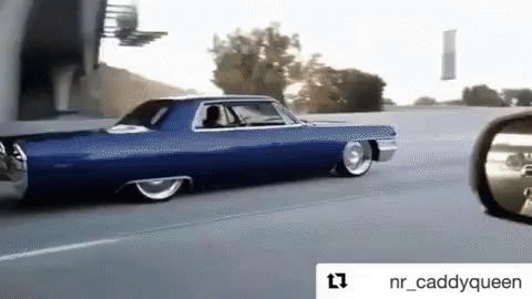 A Blue Car Is Driving Down The Road Next To A Rear View Mirror GIF