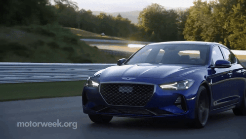 A Blue Car Is Driving On A Road With Motorweek.org Written On The Bottom Right GIF