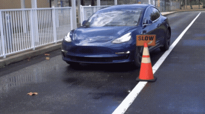 A Blue Car Is Driving Past A Slow Sign GIF