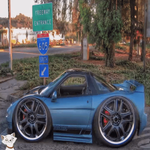A Blue Car Is Parked In Front Of A Green Freeway Entrance Sign GIF