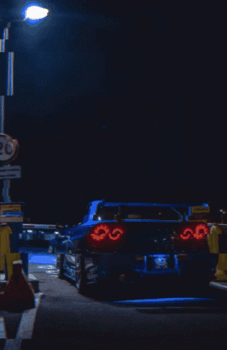 A Blue Car Is Parked In Front Of A Sign That Says 20 On It GIF