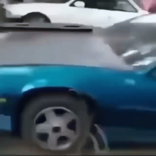 A Blue Car Is Parked Next To A White Car On A Street GIF