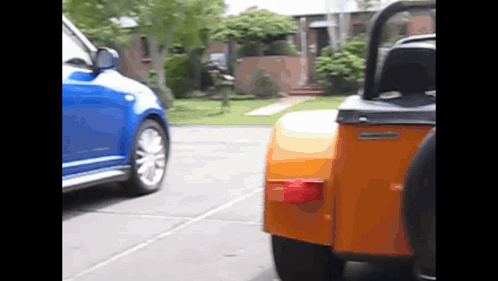 A Blue Car Is Parked Next To An Orange Vehicle GIF