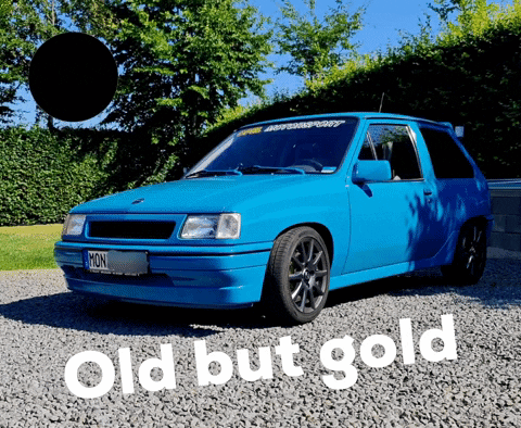 A Blue Car Is Parked On Gravel Next To A Sign That Says Old But Gold GIF