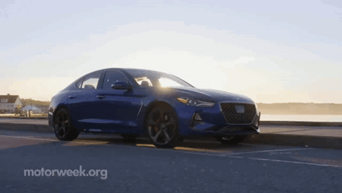 A Blue Car Is Parked On The Side Of The Road With Motorweek.org In The Corner GIF