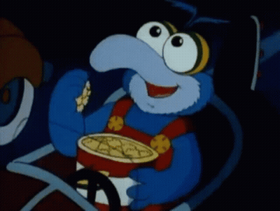 A Blue Cartoon Character Is Eating Popcorn In A Car . GIF