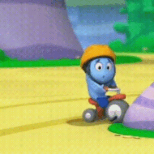 A Blue Cartoon Character Wearing An Orange Helmet Is Riding A Tricycle On A Yellow Road GIF