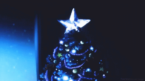A Blue Christmas Tree With A Star On Top Is Displayed In A Dark Room GIF