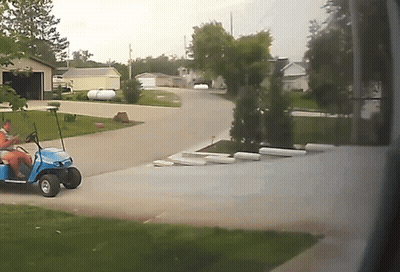 A Blue Golf Cart Is Parked In A Driveway GIF
