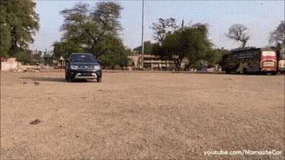 A Blue Jeep Is Driving Down A Dirt Road In Front Of A Bus GIF