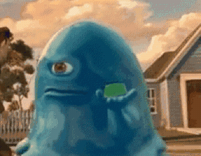 A Blue Monster With One Eye Is Holding A Green Gummy Bear In Front Of A House . GIF