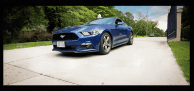 A Blue Mustang Is Driving Down A Road With A License Plate That Says ' Tcj ' On It GIF