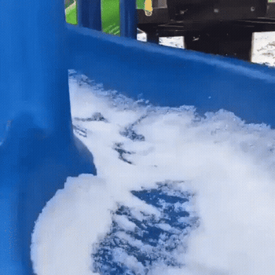 A Blue Playground Slide Covered In Snow And Foam . GIF