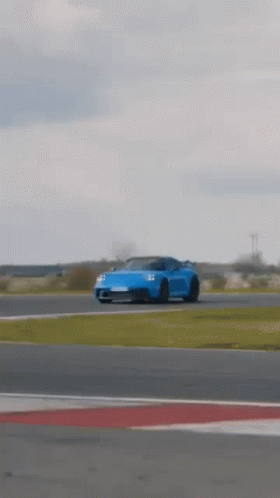 A Blue Porsche 911 Gt3 Is Driving On A Race Track . GIF