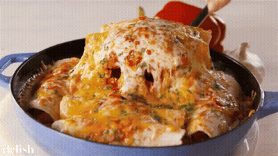 A Blue Pot Filled With Enchiladas And Cheese With The Word Delish On The Bottom GIF