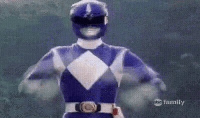 A Blue Power Ranger Is Flying Through The Air With His Arms In The Air . GIF