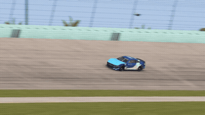 A Blue Race Car With The Word Ford On The Side Is Driving Down A Track GIF