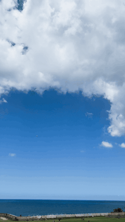 A Blue Sky With White Clouds Over The Ocean And A Golf Course In The Foreground GIF