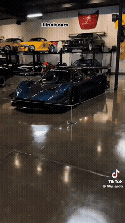 A Blue Sports Car Is Displayed In A Garage . GIF