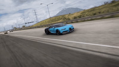 A Blue Sports Car Is Driving Down A Highway With A Mountain In The Background GIF