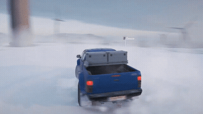 A Blue Truck Is Driving Through The Snow With A Sign That Says Snooper GIF